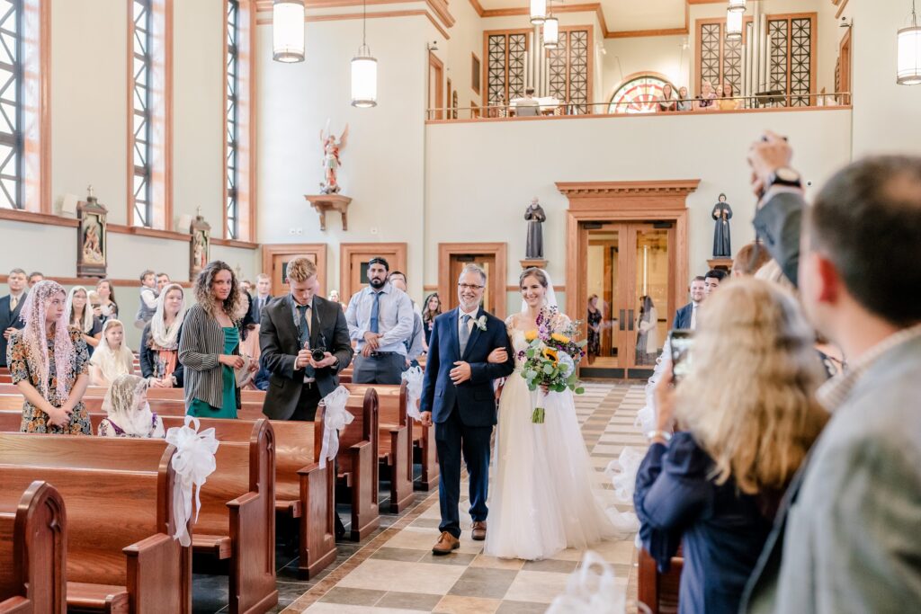 A bride and her father walking down the aisle for her Catholic wedding in Fredericksburg VA