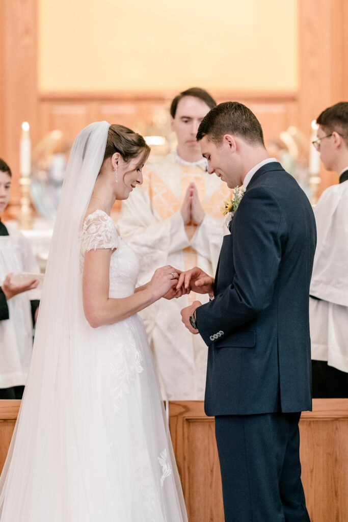 A bride and groom exchange rings during their wedding at St. Patrick Catholic Church in Fredericksburg VA