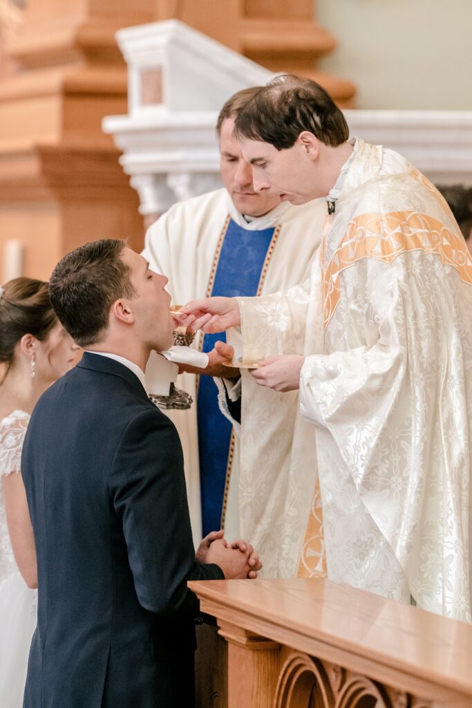 A groom receiving communion during his wedding