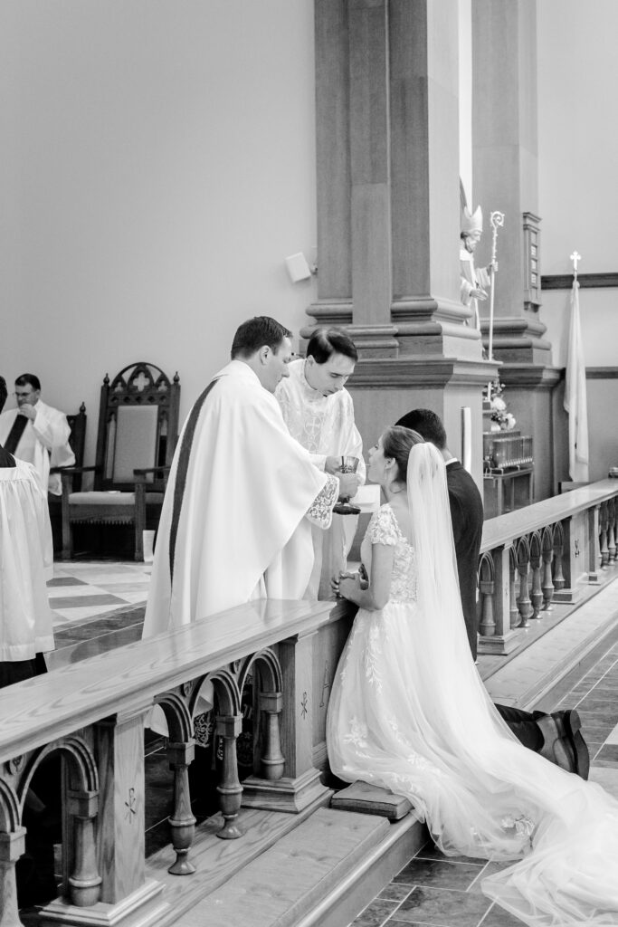 A bride receiving communion during her wedding at St. Patrick Catholic Church in Fredericksburg, VA