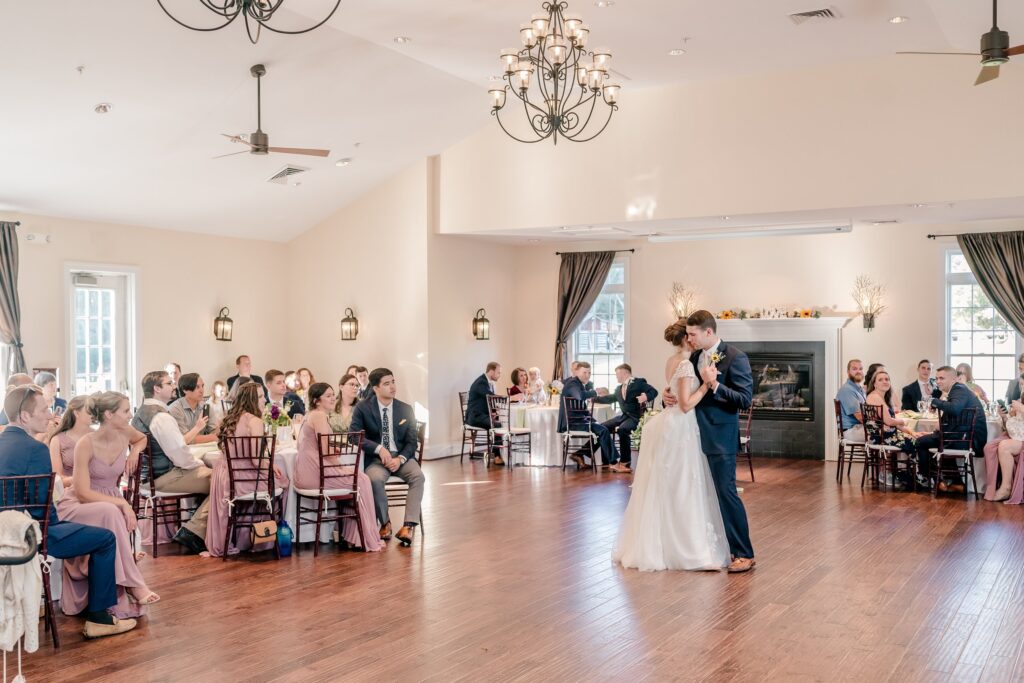 A wide shot of the bride and groom's first dance surrounded by tables of guests