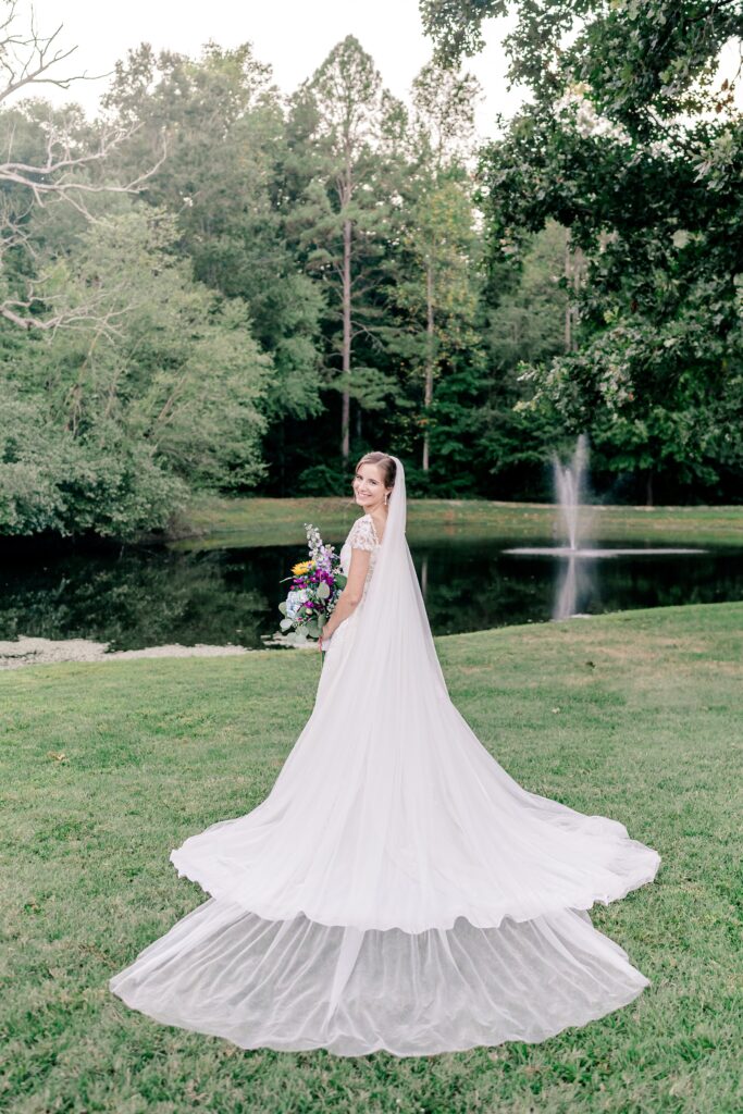 A bride poses to show off her cathedral veil and large bouquet during her Catholic wedding in Fredericksburg VA