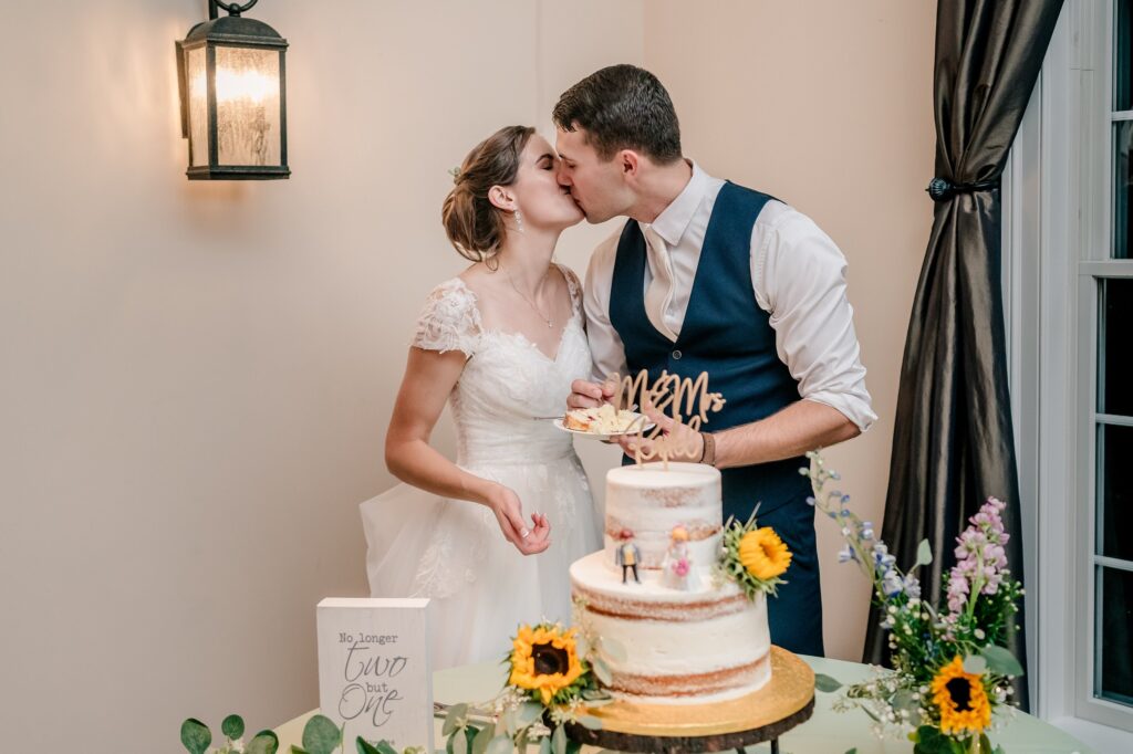 A bride and groom share a kiss at their cake cutting during their Catholic wedding in Fredericksburg VA