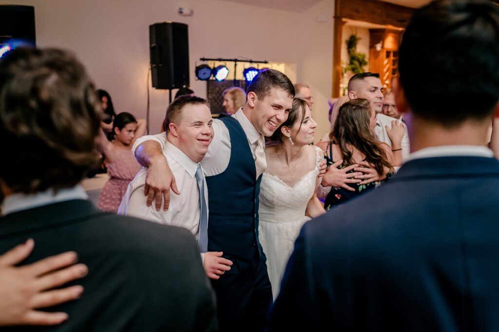 A bride and groom smiling on the dance floor with their guests