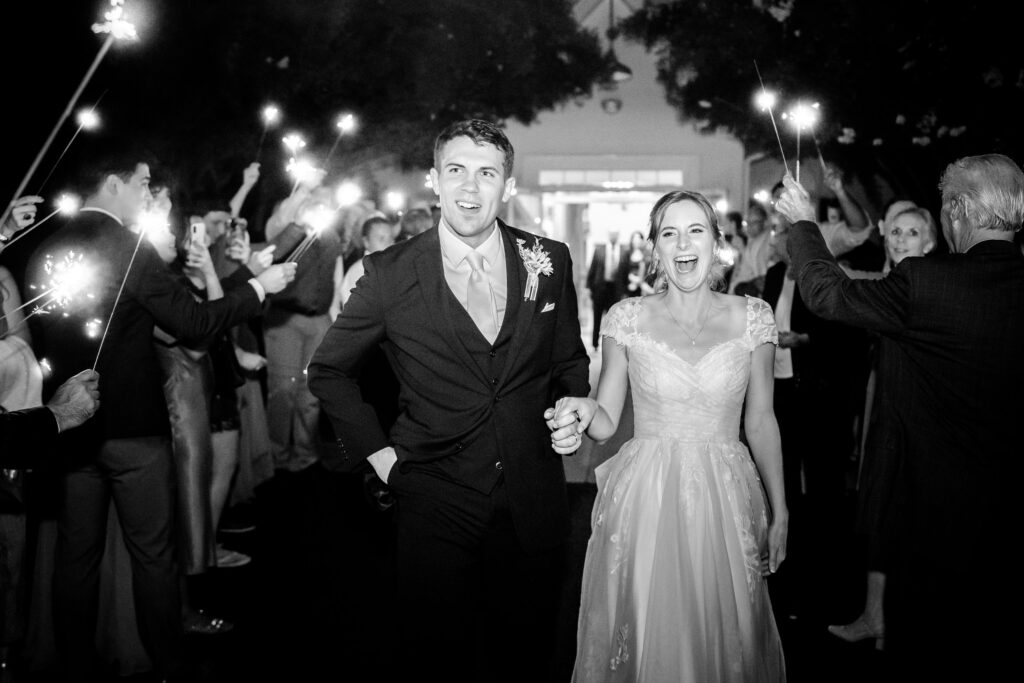 A bride and groom smile at guests holding sparklers during their Catholic wedding in Fredericksburg VA