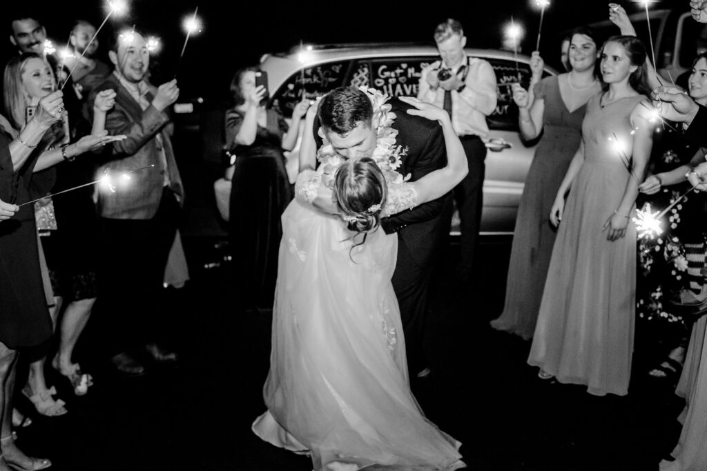 A bride and groom share a dramatic dip kiss during their sparkler sendoff