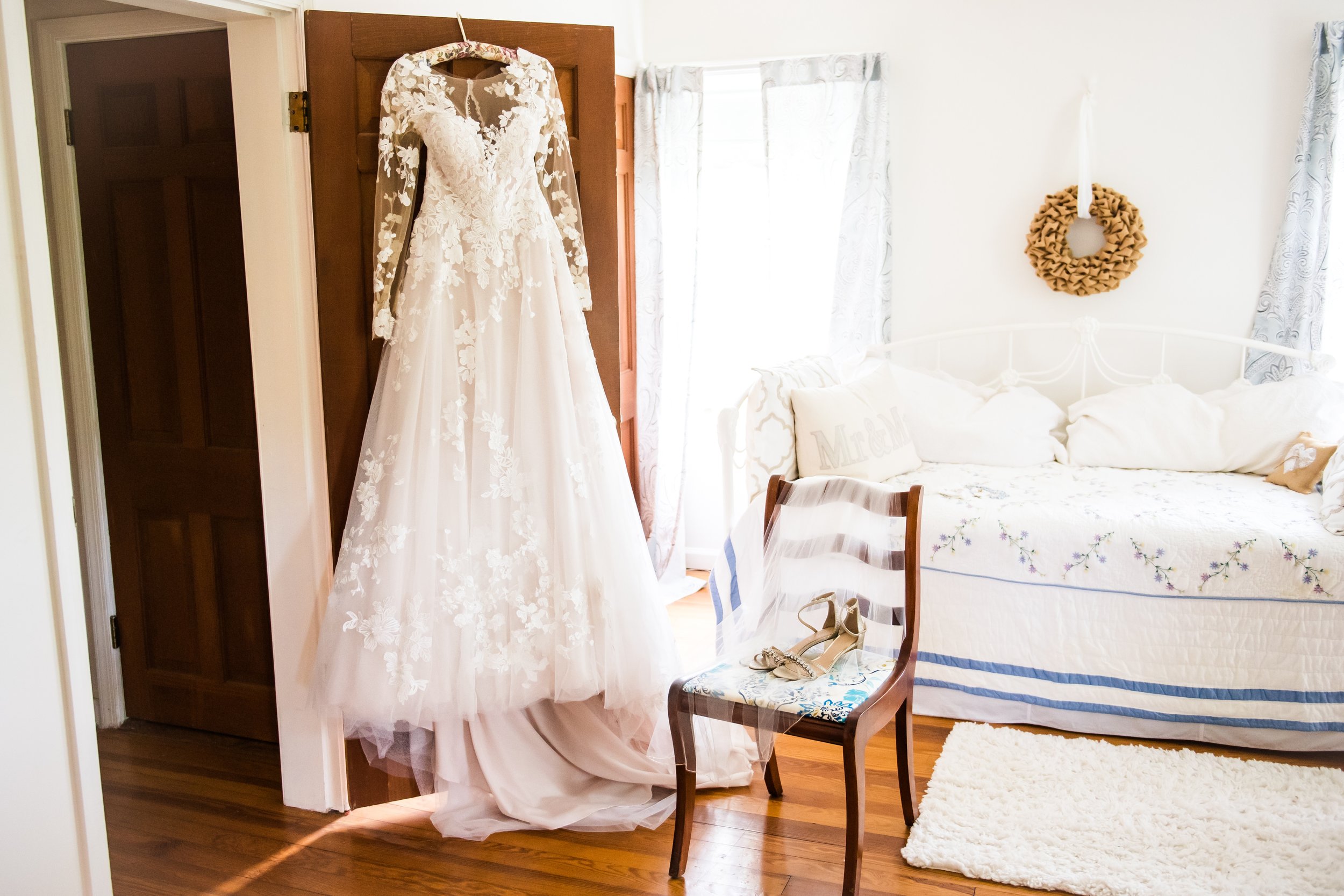 A bride's dress hanging in the getting ready suite before a wedding at The Barns at Hamilton Station Vineyard in Loudoun County, Virginia