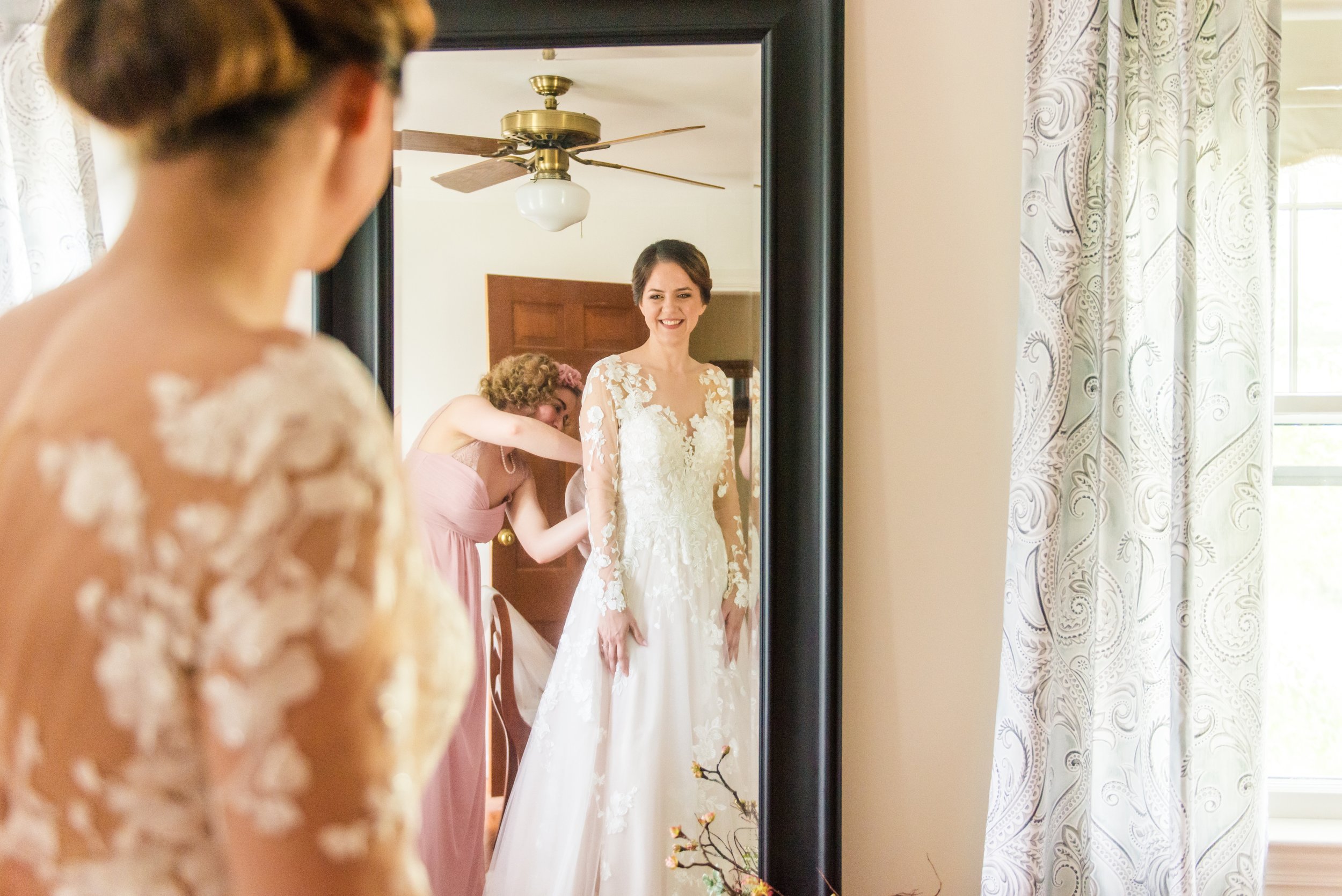 A bride looking in the mirror of the getting ready suite before her wedding at The Barns at Hamilton Station Vineyard in Leesburg, Virginia