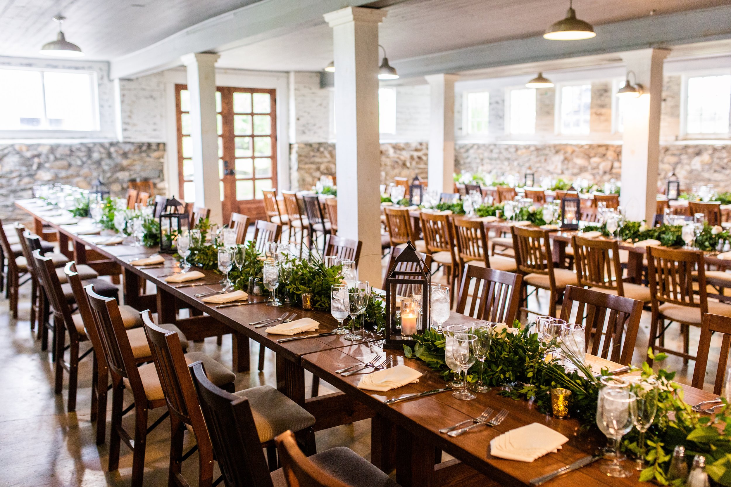 A dinner reception set up in the lower room of the main barn for a wedding at the best vineyard wedding venue in Loudoun County