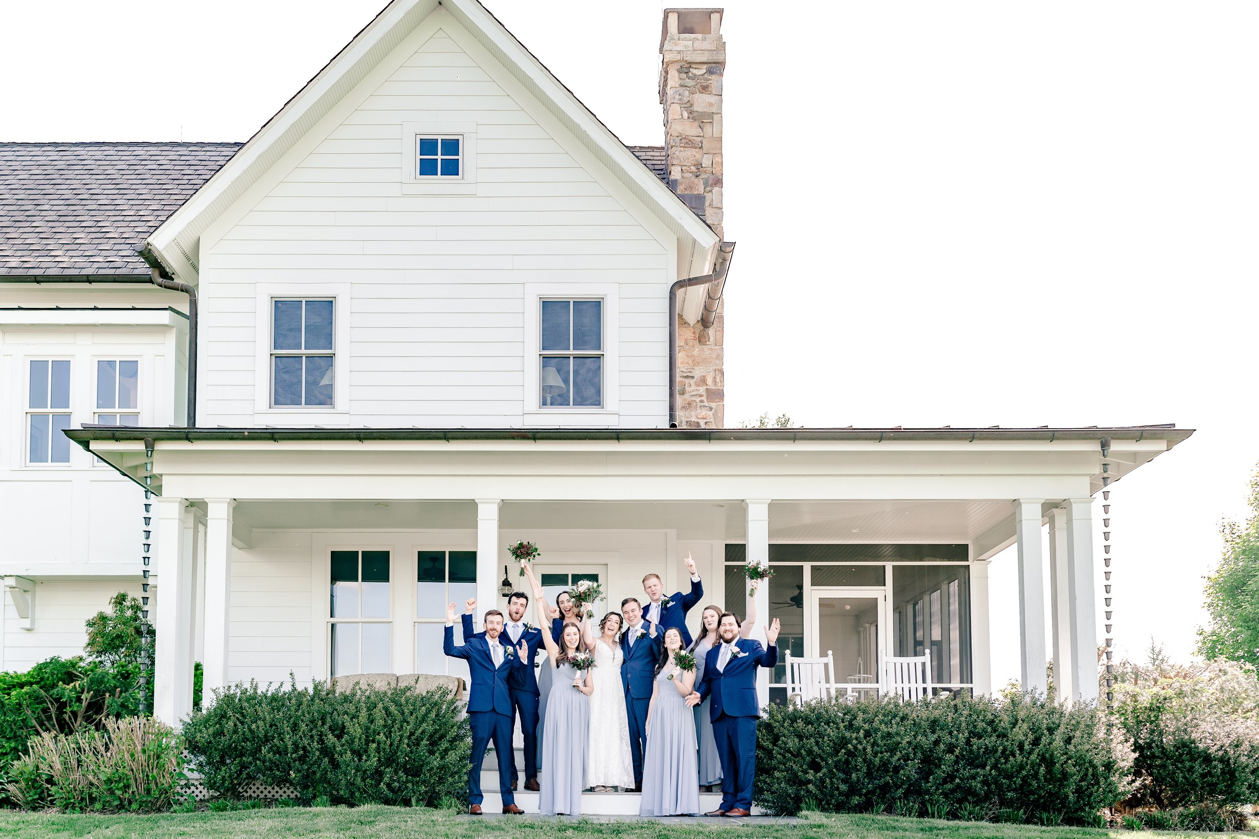 A wedding party posed on the porch of the farm house at one of the best wedding venues in Northern Virginia