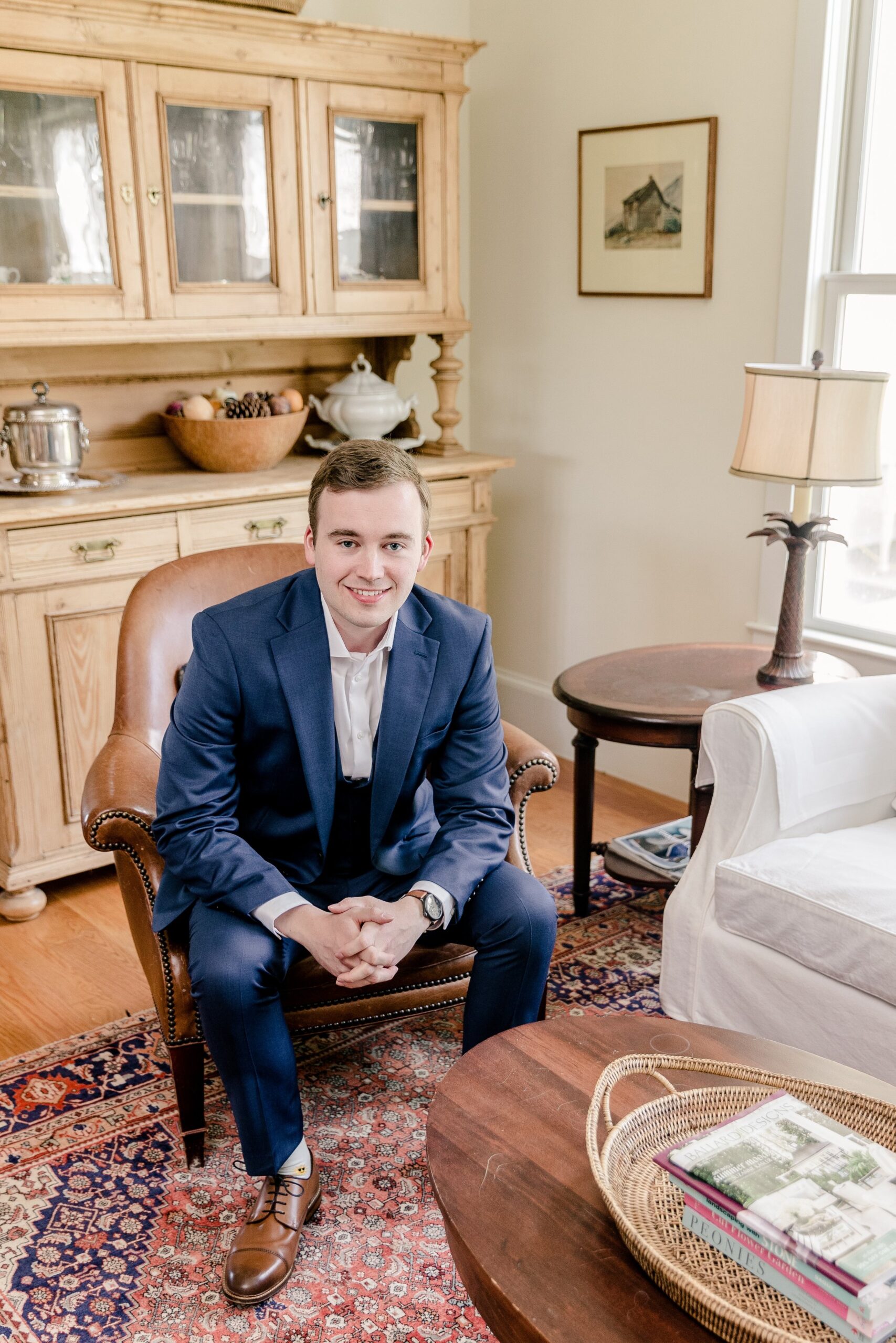 A groom seated in the living room of a farm house before his wedding at Blue Hill Farm in Loudoun County Virginia