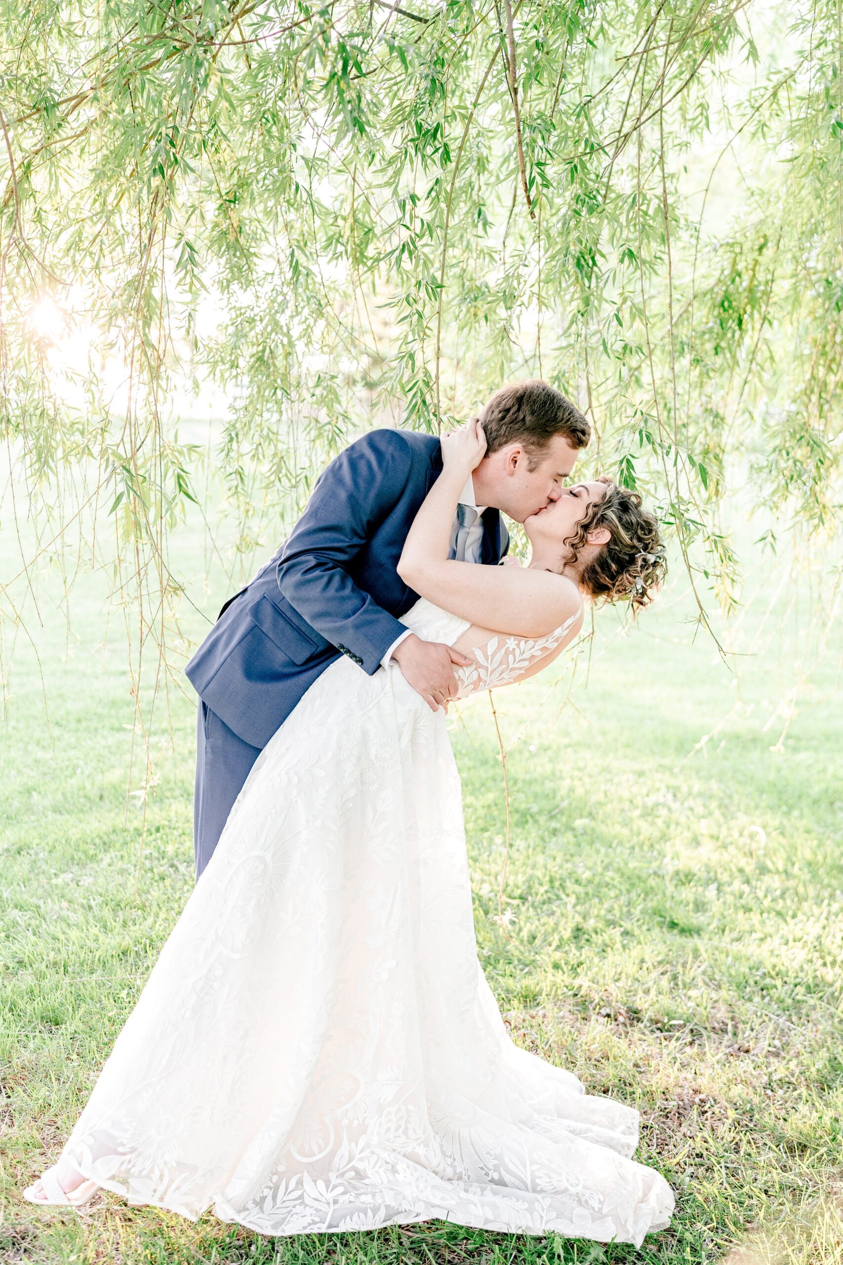 A bride and groom share a kiss under a tree during their wedding at Blue Hill Farm in Round Hill, Virginia