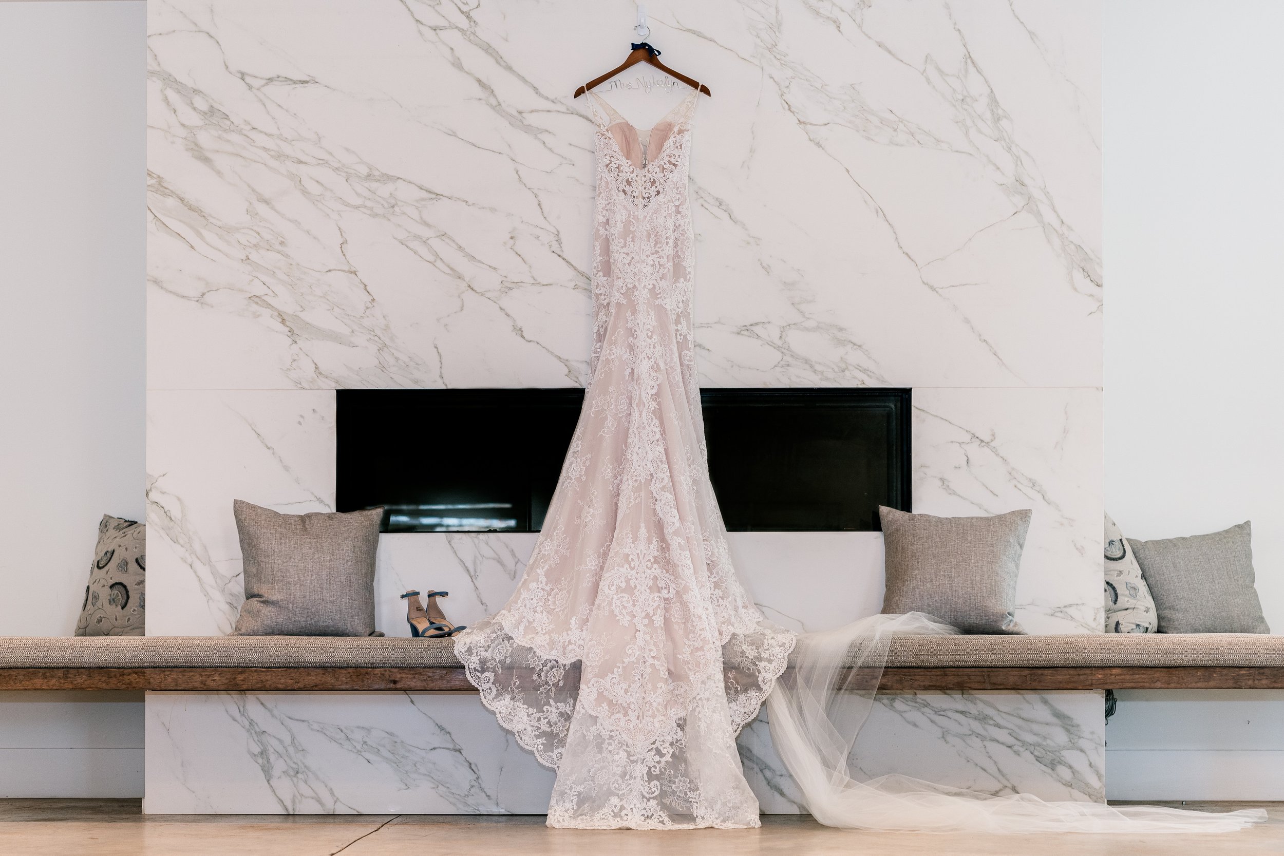 A wedding dress hanging in front of a marble fireplace at one of the Best Wedding Venues in Loudoun County Virginia