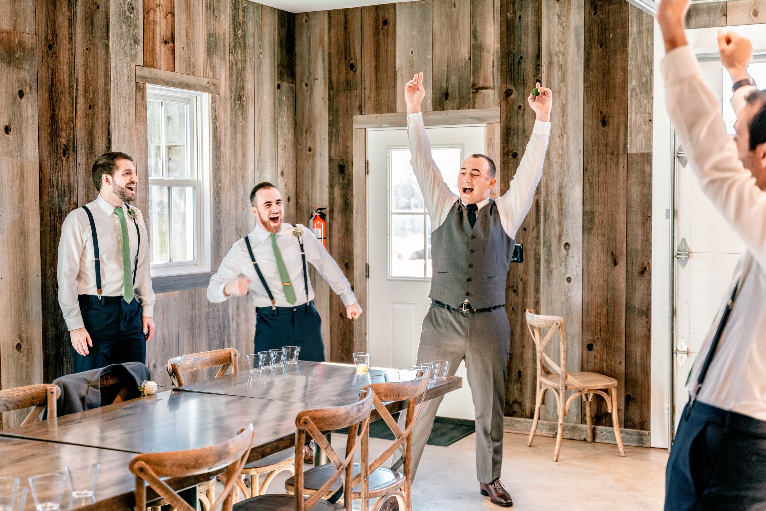A groom and his groomsmen cheer while playing a game before his wedding at Fleetwood Farm Winery in Leesburg Virginia
