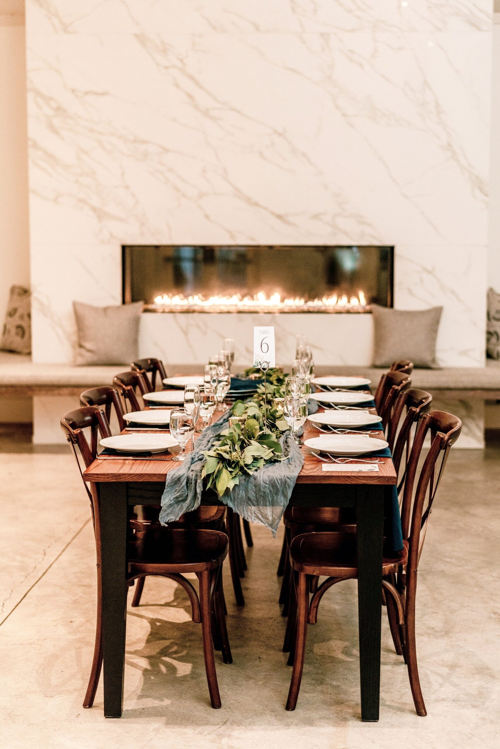 A dinner table in front of the marble fireplace set up at the reception for a wedding at Fleetwood Farm Winery in Leesburg Virginia
