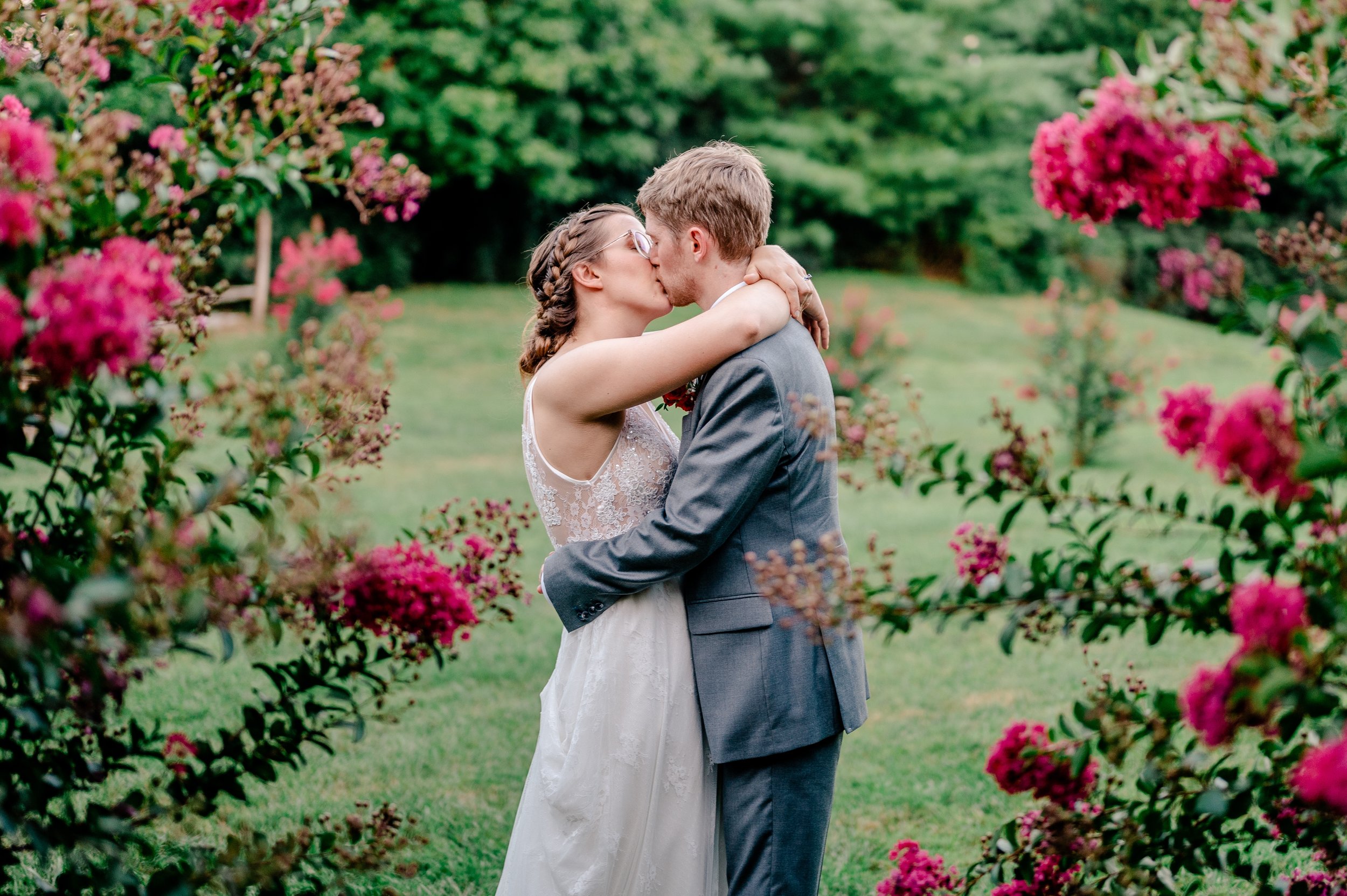 A bride and groom share a kiss surrounded by flowers during their wedding at Rose Hill Manor in Leesburg Virginia