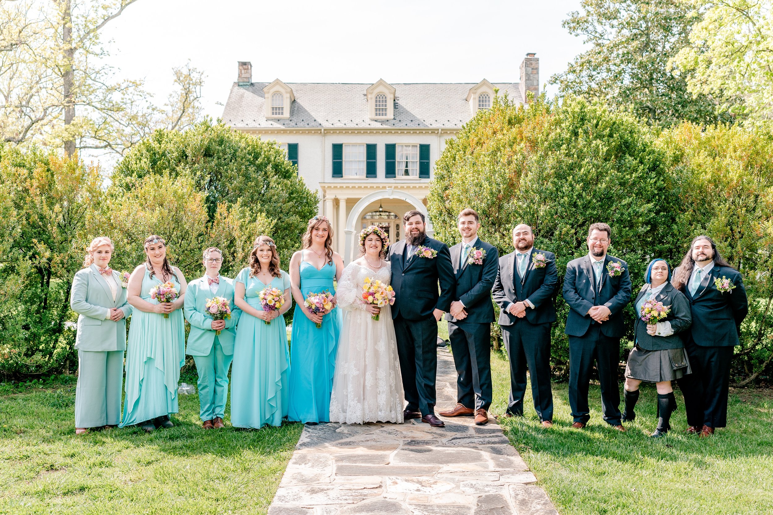 A bridal party dressed in shades of aqua standing in front of the historic house at one of the best wedding venues in Northern Virginia