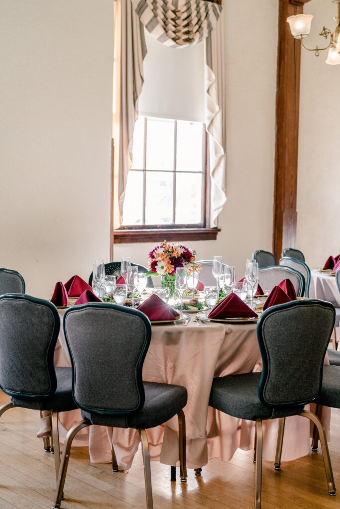 A dinner table with blue chairs and red napkins set for a wedding reception at Fairfax Old Town Hall in Northern Virginia