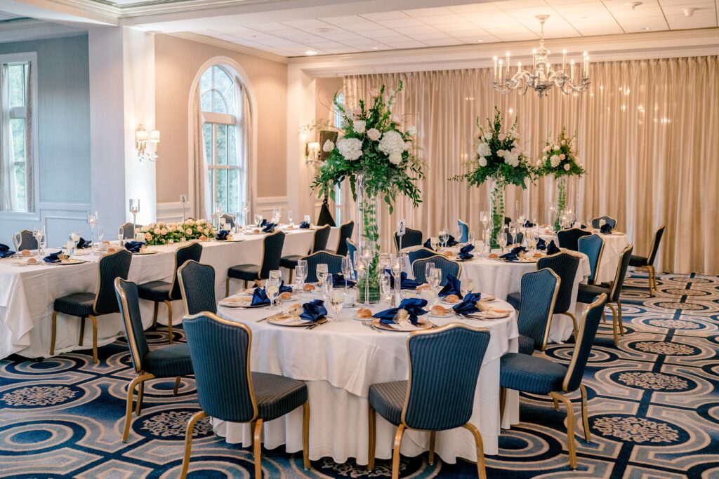 A dinner reception table featuring a tall centerpiece with white flowers at one of the best wedding venues in Northern Virginia