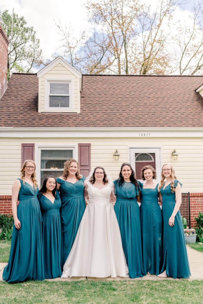 A bridal party posed outside the bride's home where they got ready for her Catholic wedding