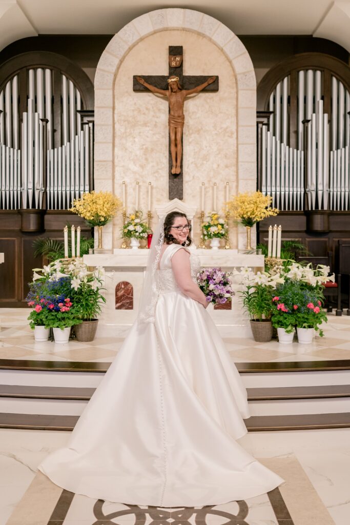 A bride posed for a portrait in front of the altar after her Catholic wedding at St. Joseph's Church in Cockeysville, Maryland