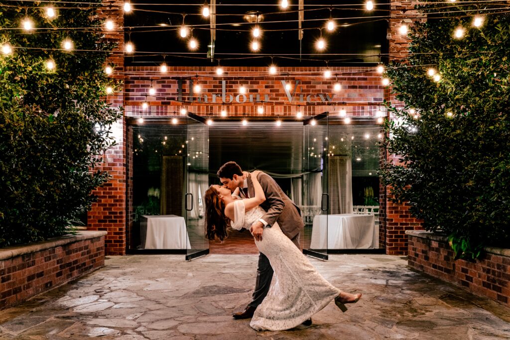 A bride and groom kiss under string lights at one of the best wedding venues in Northern Virginia