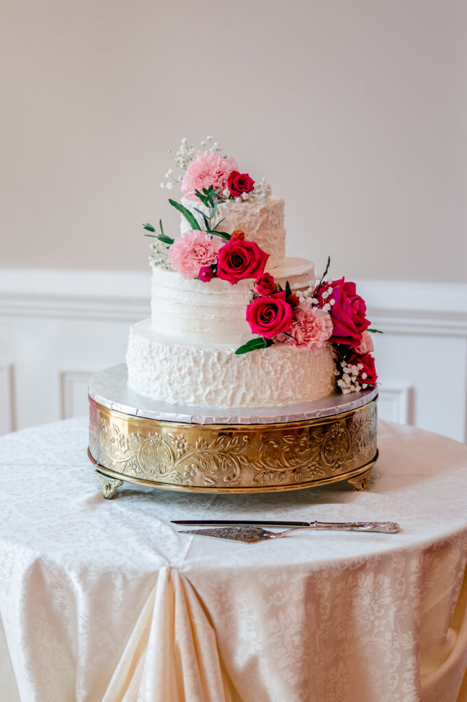 Hot pink flowers cascade down a buttercream cake for pink wedding cake inspo