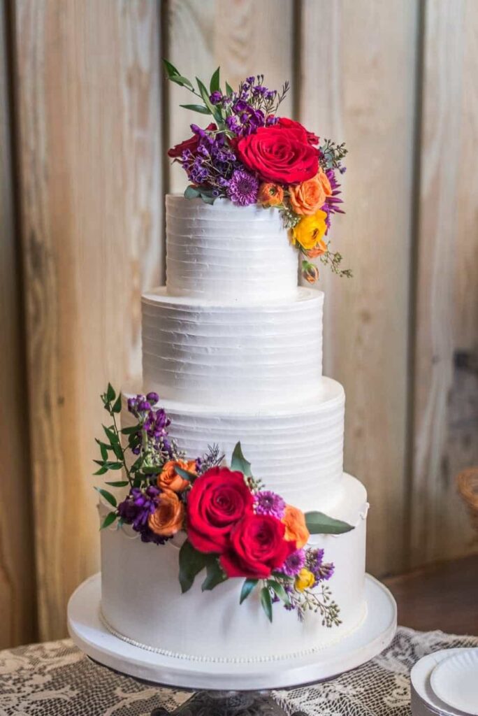 A four tier wedding cake decorated with vibrant flowers