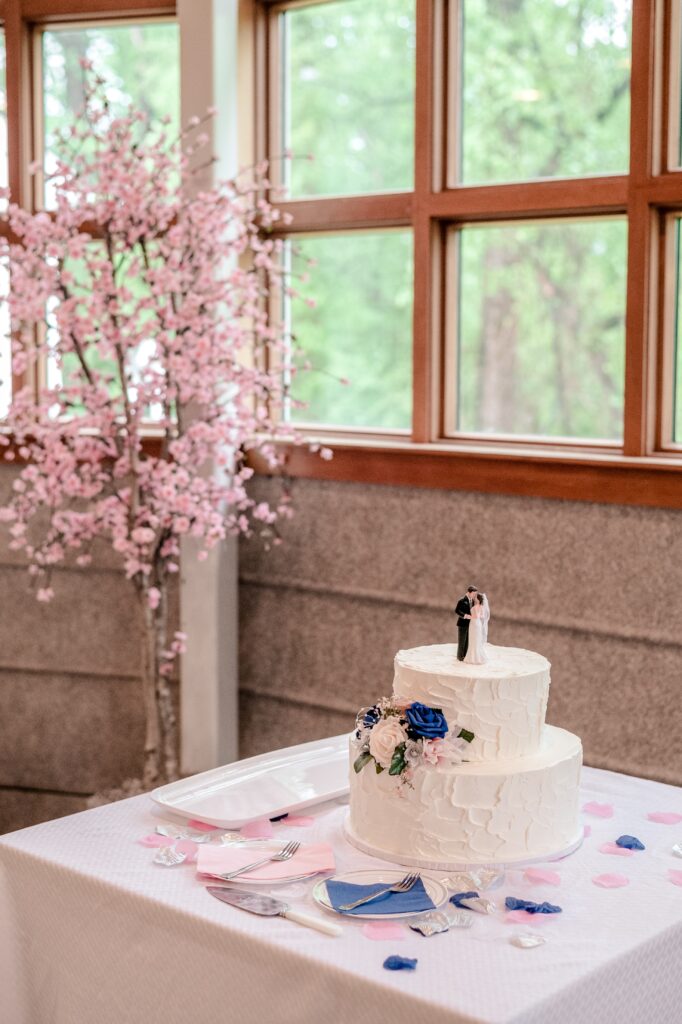 A buttercream wedding cake with a unique texture beside a blooming cherry blossom tree