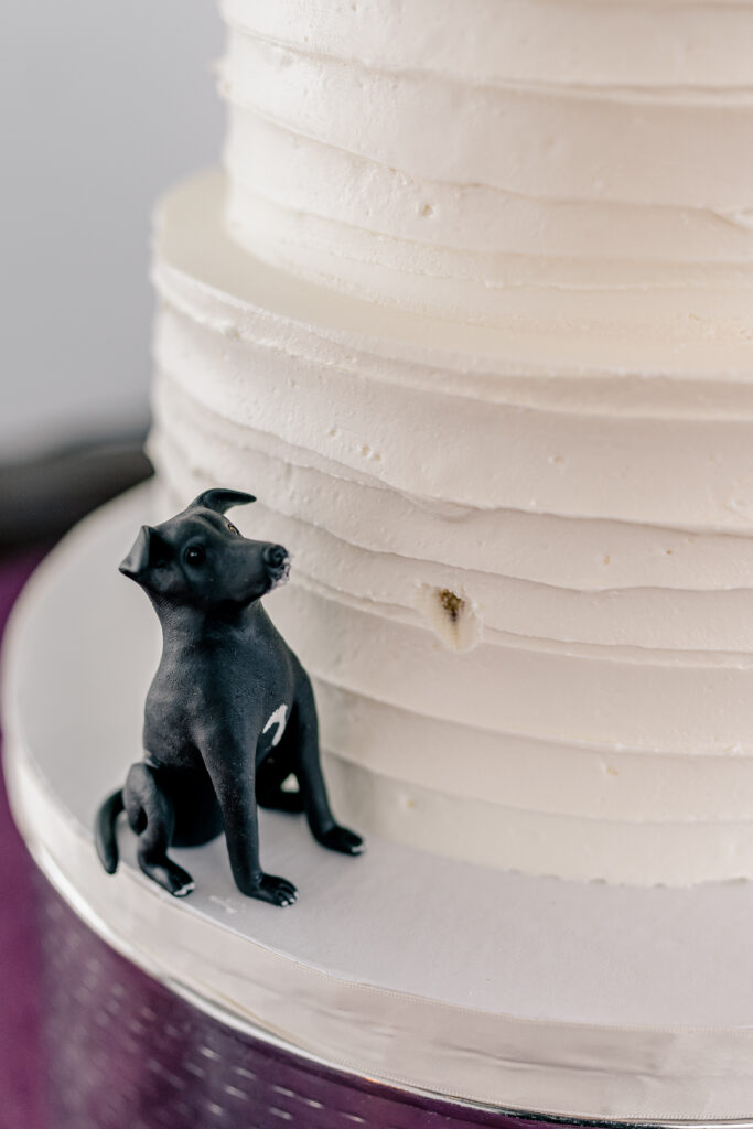 A fondant dog made to look like it is eating the wedding cake