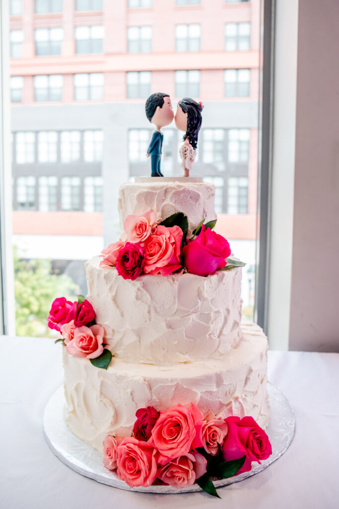 A buttercream wedding cake with vibrant flowers and a custom cake topper