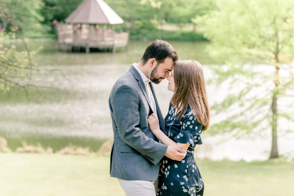 A couple poses in front of a pond with a gazebo during their Meadowlark Botanical Gardens engagement session