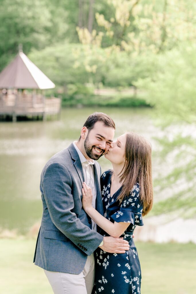 A woman kisses her beloved on the cheek during their Meadowlark Botanical Gardens engagement session