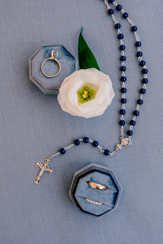 A flat lay of a rosary and rings for a wedding at St Philip Catholic Church in Falls Church Virginia