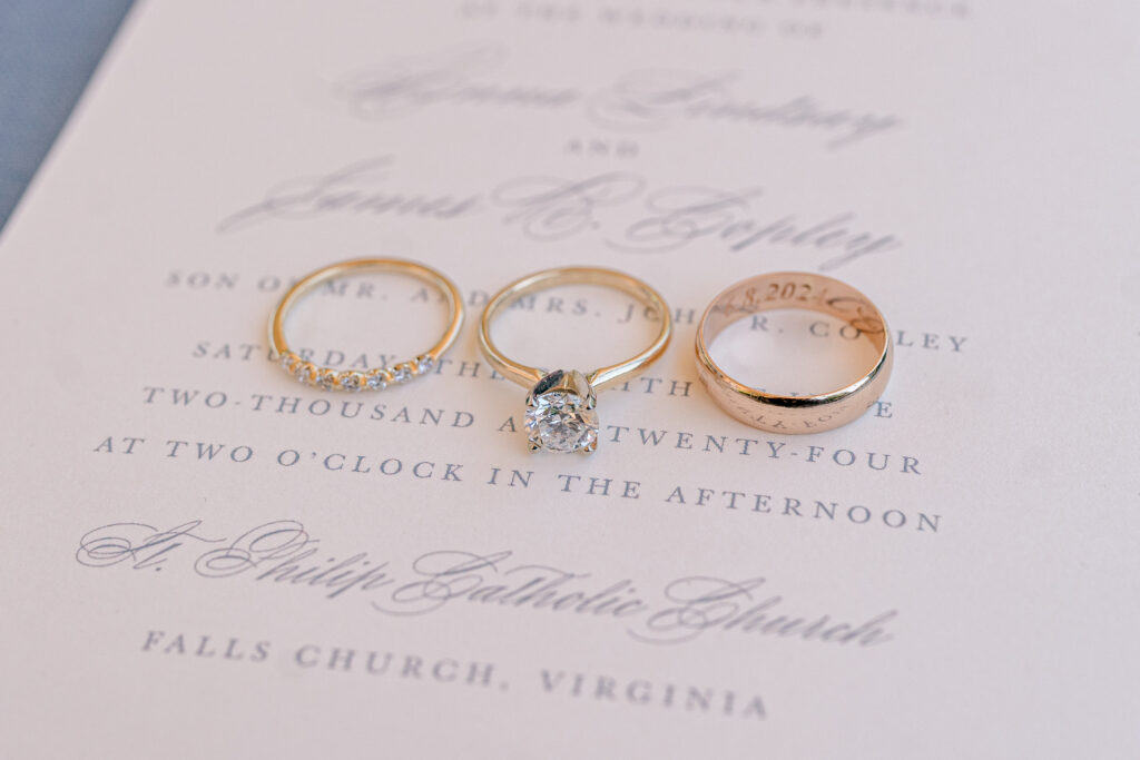 Rings placed on an invitation for a wedding at St Philip Catholic Church in Falls Church Virginia