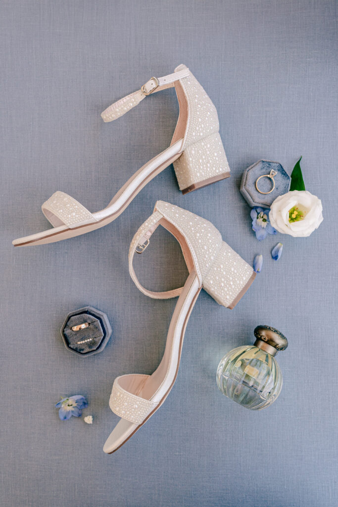 Bridal shoes and details on a blue backdrop for a wedding at St Philip Catholic Church in Falls Church Virginia