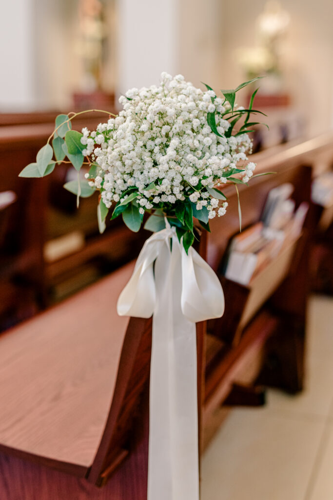 A bundle of baby's breath tied with a white ribbon on a pew for a wedding at St Philip Catholic Church in Falls Church Virginia