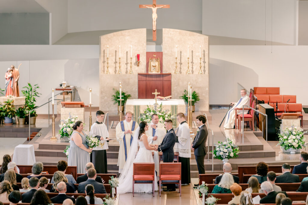 A bride and groom exchanging vows in front of the altar during a wedding at St Philip Catholic Church in Falls Church Virginia