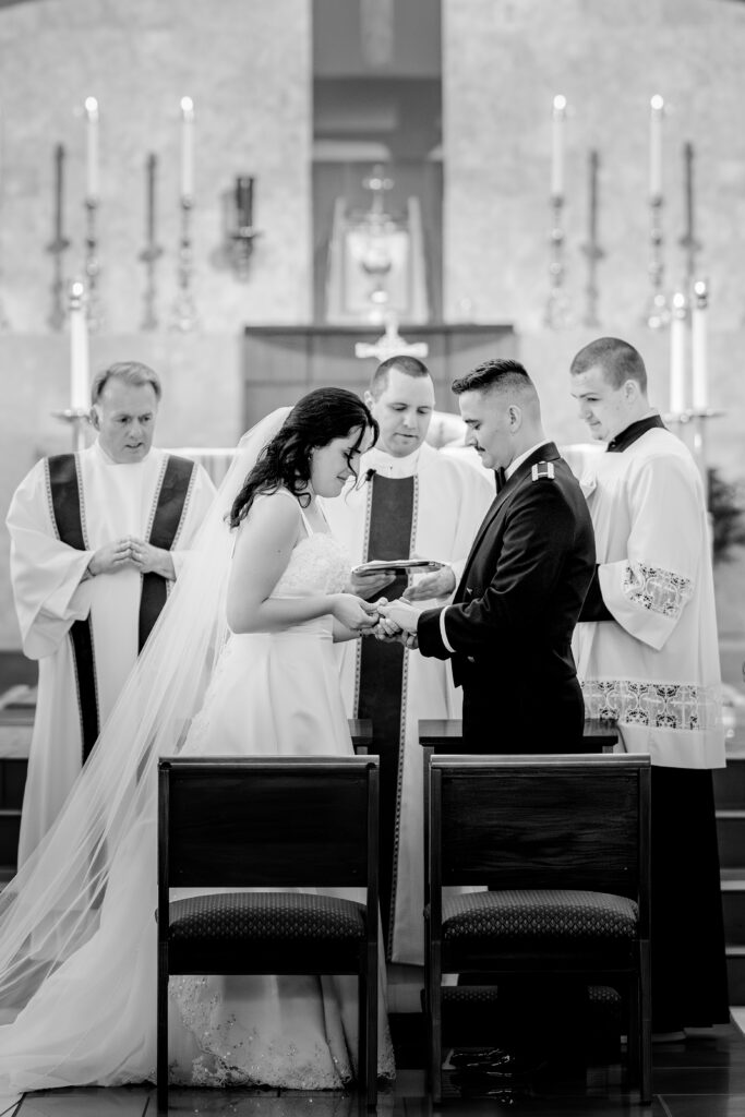 A bride and groom exchanging rings during a wedding at St Philip Catholic Church in Falls Church Virginia