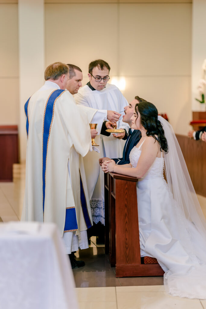 A groom receiving Communion during a wedding at St Philip Catholic Church in Falls Church Virginia