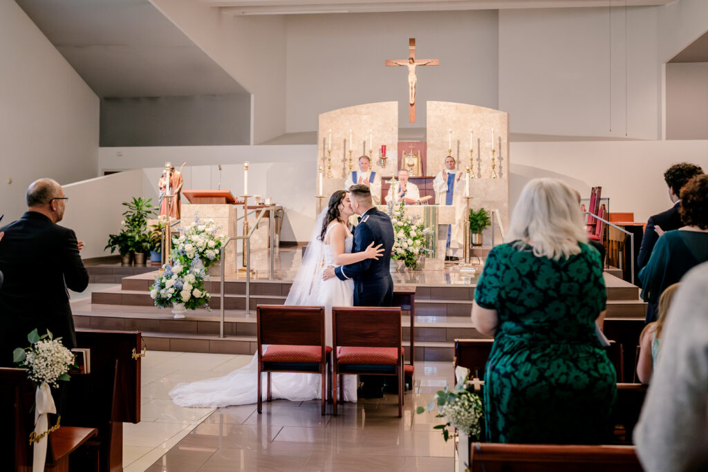 A bride and groom sharing their first kiss as husband and wife during a wedding at St Philip Catholic Church in Falls Church Virginia