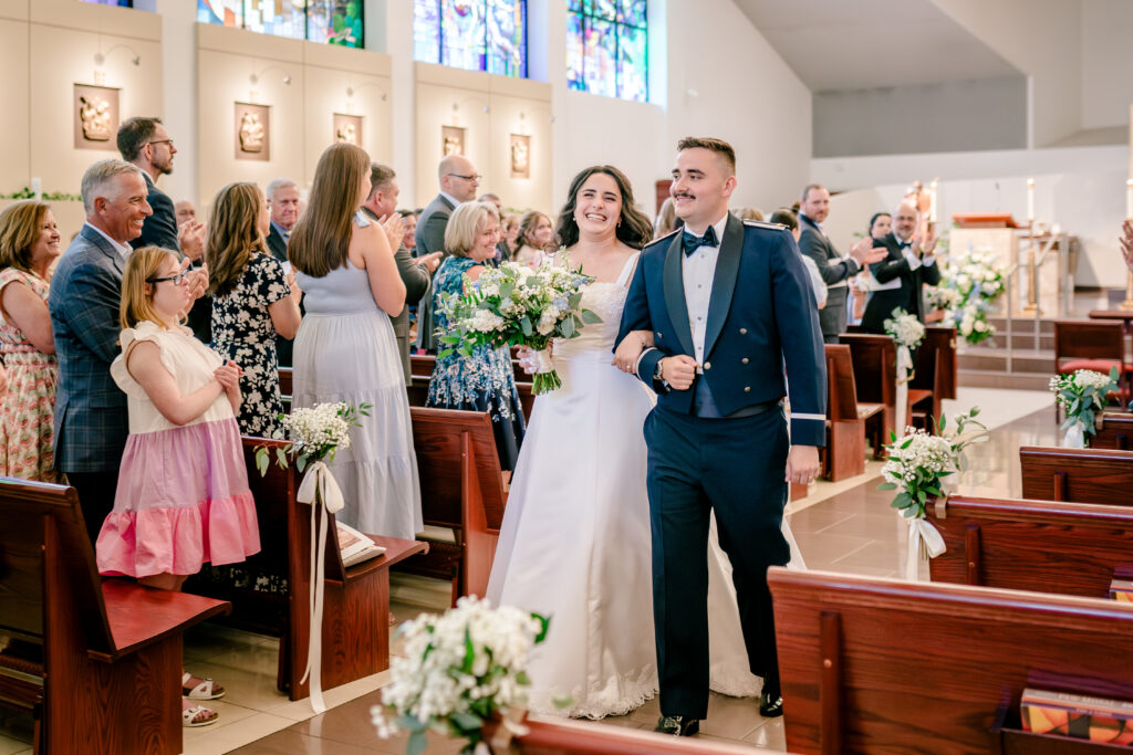 The bride and groom smiling as they walk back up the aisle after a wedding at St Philip Catholic Church in Falls Church Virginia