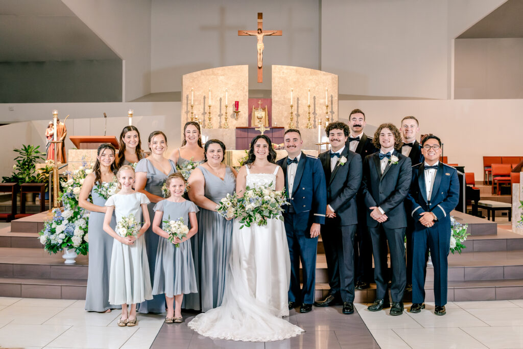 A wedding party posed for a formal portrait inside the church after a wedding at St Philip Catholic Church in Falls Church Virginia