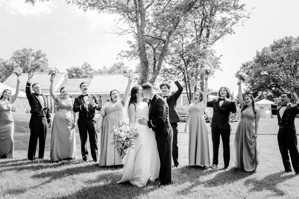 A wedding party cheering as the bride and groom share a kiss during a tented wedding reception at Historic Blenheim in Fairfax, Virginia