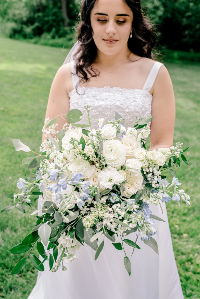 A close up of a bridal bouquet featuring white and soft blue flowers during a tented wedding reception at Historic Blenheim in Fairfax, Virginia