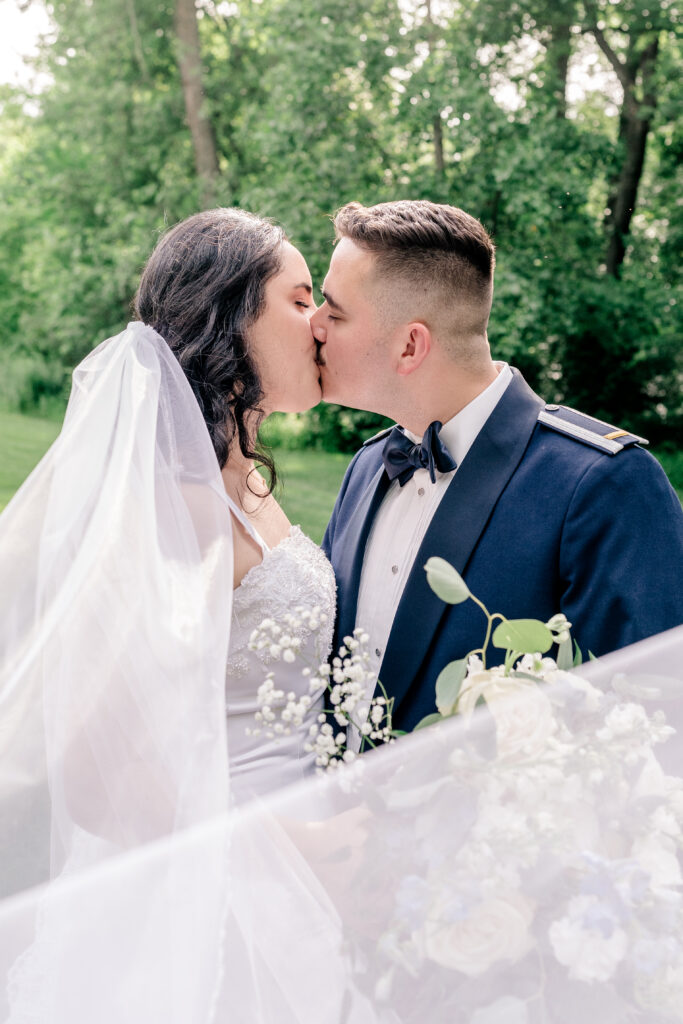 A bride and groom share a kiss with her veil flowing into the foreground during a tented wedding reception at Historic Blenheim in Fairfax, Virginia