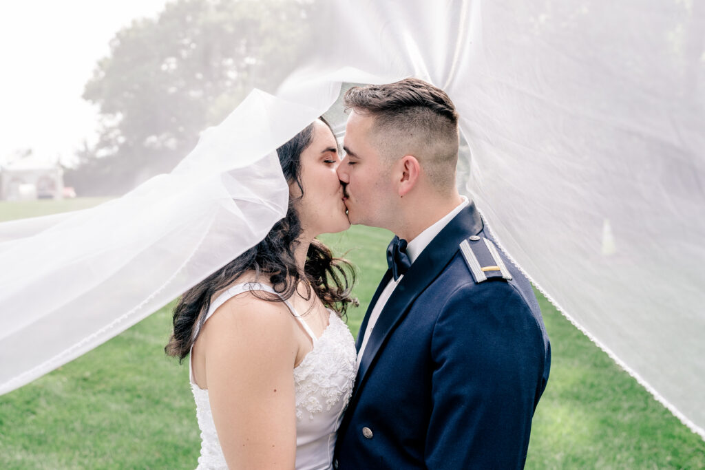 A bride and groom share a kiss under the veil during a tented wedding reception at Historic Blenheim in Fairfax, Virginia