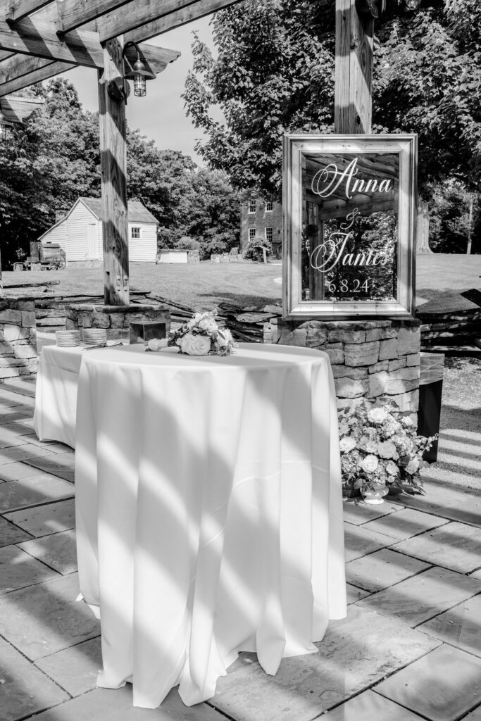 Cocktail hour tables in front of a mirror that reads Anna and James during a tented wedding reception at Historic Blenheim in Fairfax, Virginia