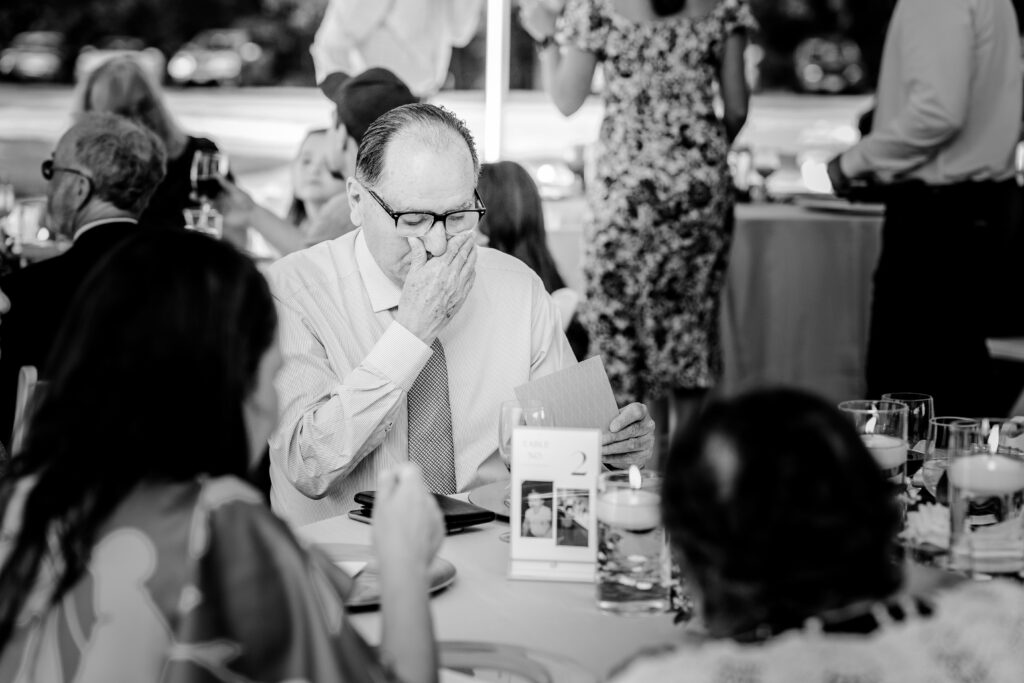 A wedding guest getting emotional as he reads a personalized thank you card from the bride and groom during a tented wedding reception at Historic Blenheim in Fairfax, Virginia