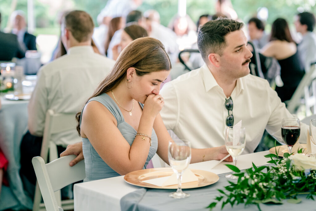 A bridesmaid getting emotional as she reads a personalized thank you card from the bride and groom during a tented wedding reception at Historic Blenheim in Fairfax, Virginia